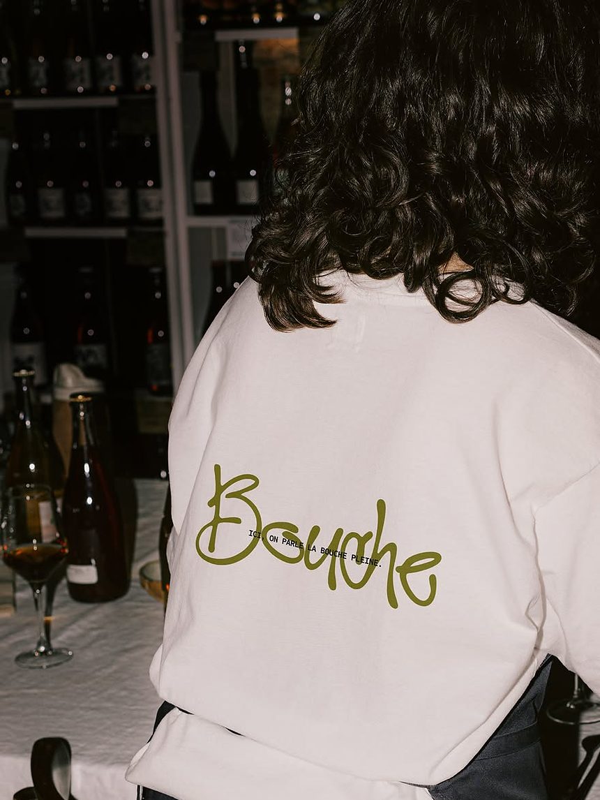 Les étagères de vins nature derrière le comptoir, une bouteille ouverte sur la table